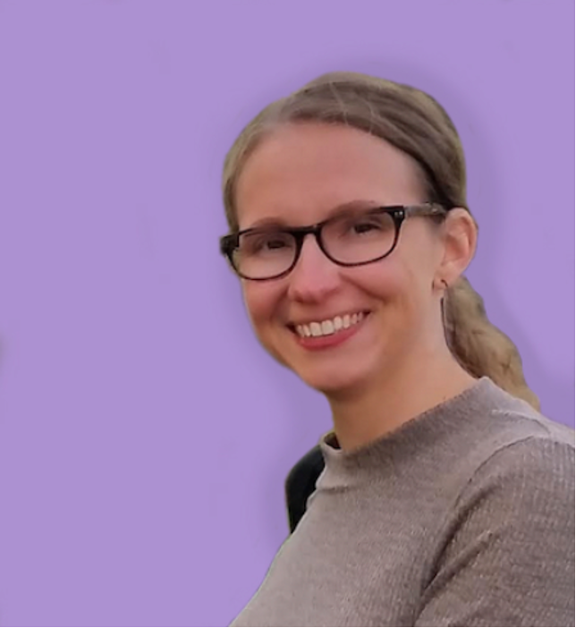 Dr. FitzPatrick, a white person with dirty blonde curly hair pulled back into a ponytail and dark-framed rectangular glasses. She has a thin hoop earring and is smiling widely, looking into the camera. She is wearing a beige turtleneck sweater, with a dark backpack strap across her far shoulder, against an edited solid-color bright lilac background.