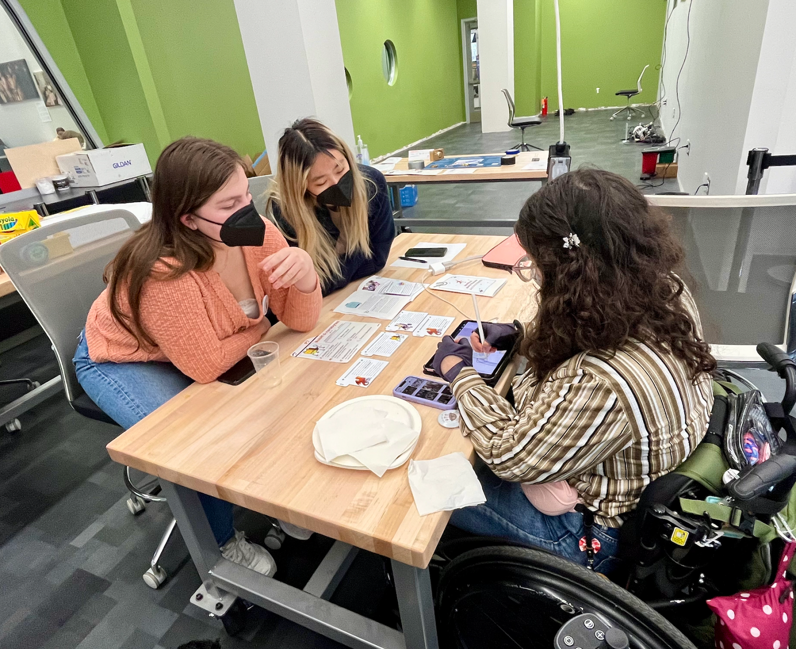 A group of three students gathered around a table looking at materials for the D.I.S.C.O. workshop.